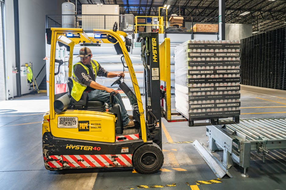 A man using a forklift to lift a pallet of goods in a warehouse