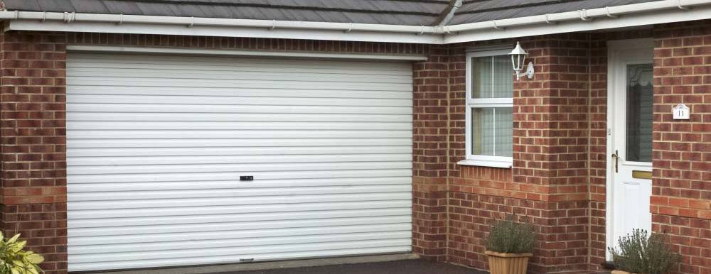 White roller shutter garage doors installed in a brick bungalow 