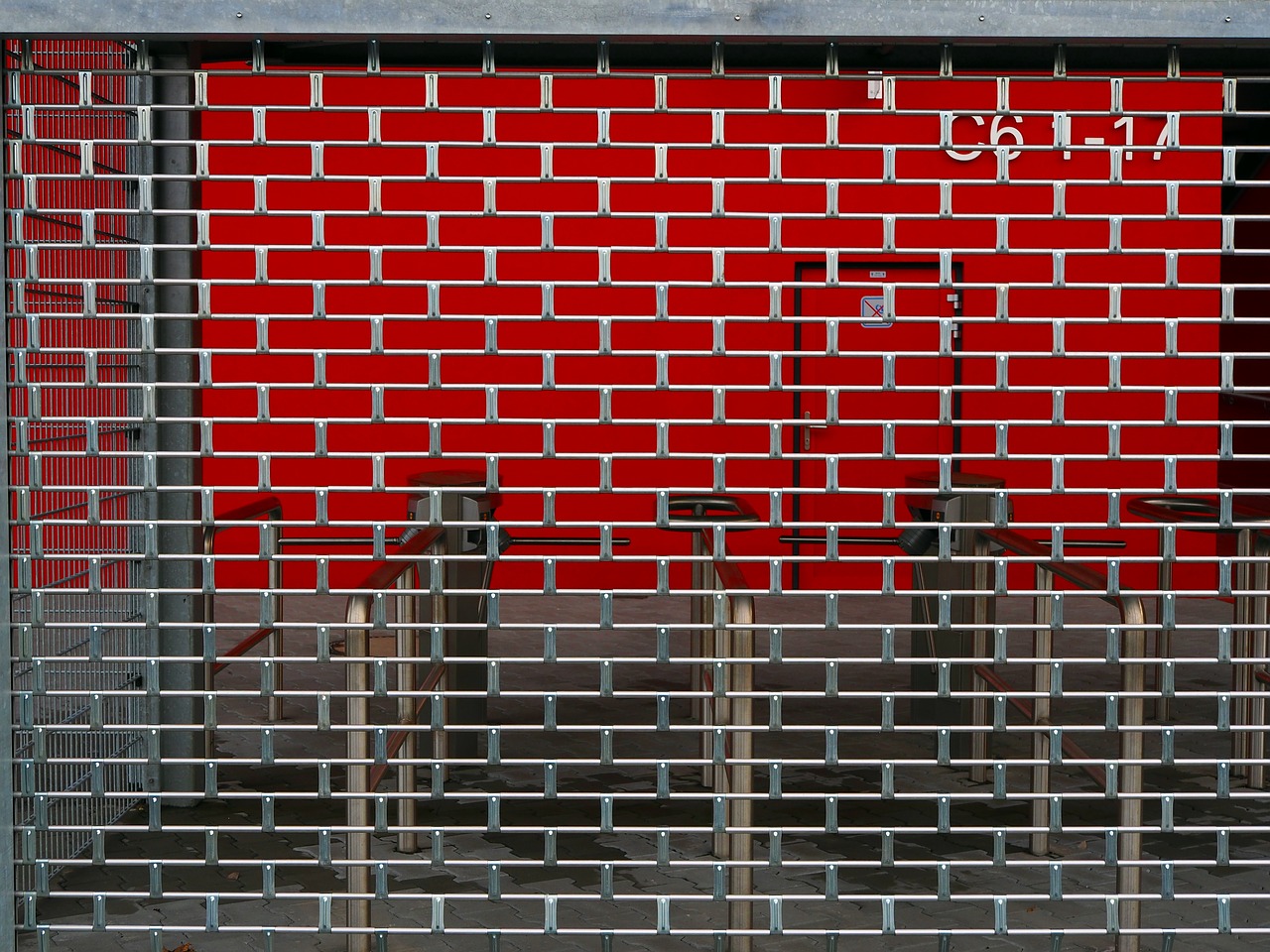 A closed metal grill on the front of a shop entrance. 